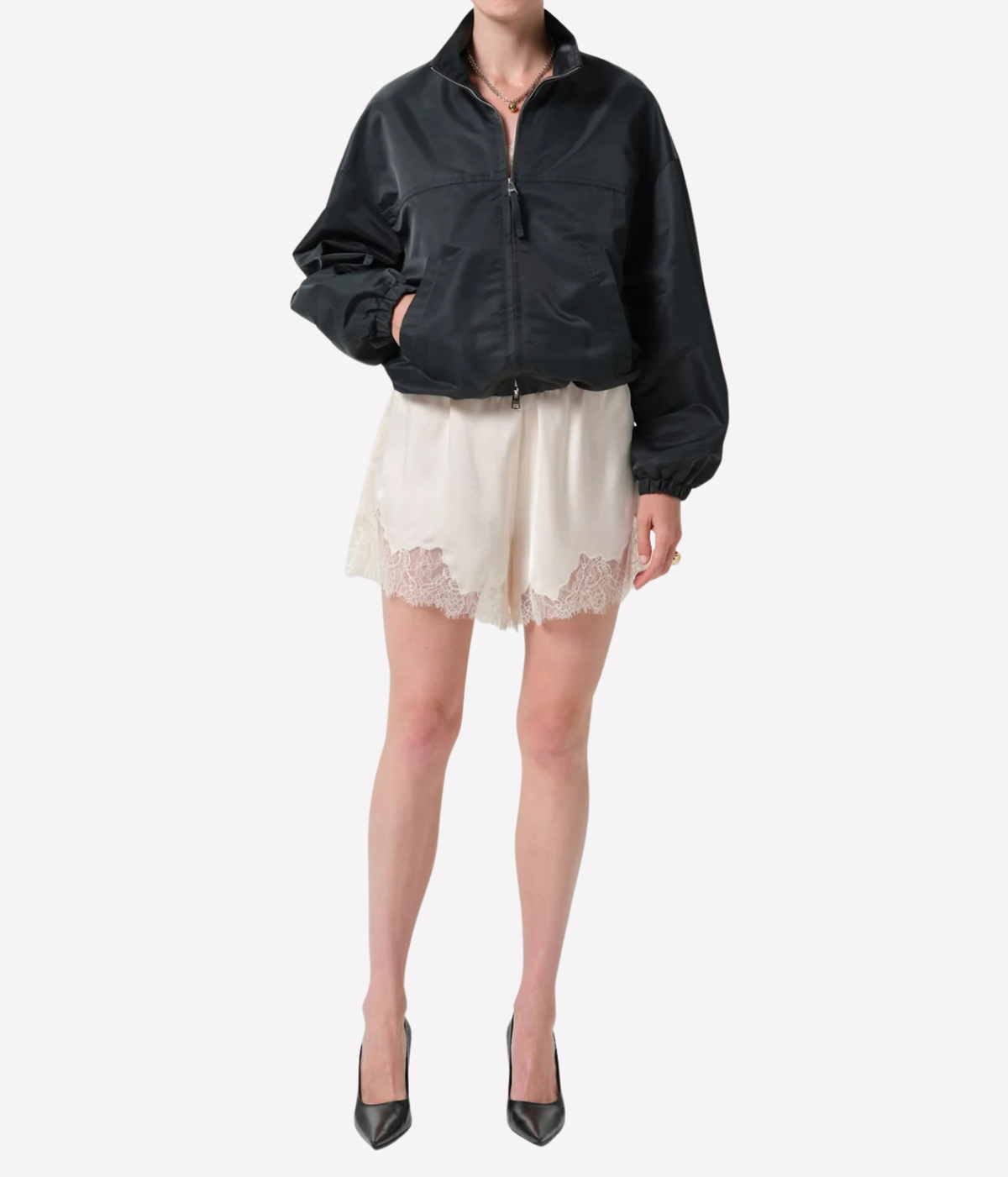 A model is shown from the neck down wearing a black zip-up bomber jacket, cream lace-trimmed shorts - Lace Trimmed Tap Short in cream