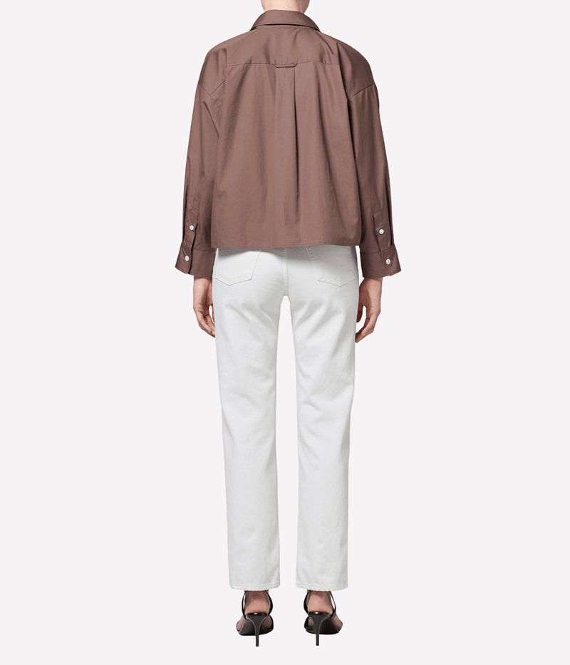 Back view of a model wearing the Citizens Of Humanity 90s French High Rise Straight in vintage white with a brown shirt and black strappy heels, showing the back of the straight leg and hem