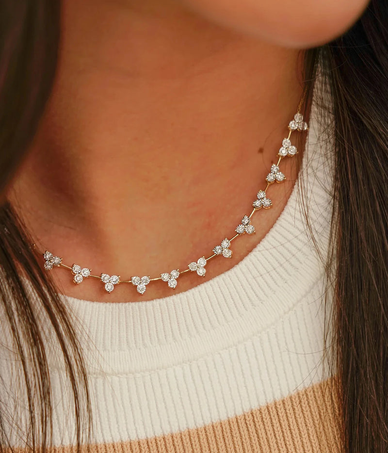 Model wearing the Dana Rebecca Designs Ava Bea Interval Trio Tennis Necklace in 14k Yellow Gold close to the neck with a cream knit top