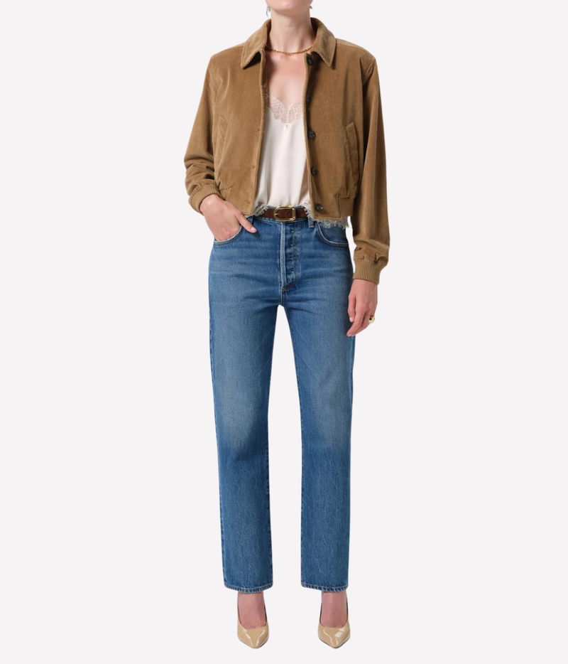 Full-length front view of a model wearing the Citizens of Humanity 90s French Straight in Pastis with a tan cropped jacket open over a cream top, a brown belt and nude pointed heels