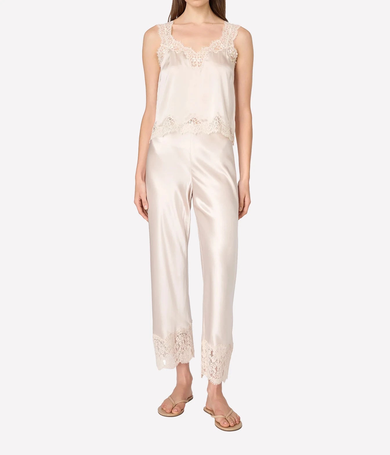 A woman modeling a satin set with a camisole top and matching cropped pants, featuring lace trim at the neckline