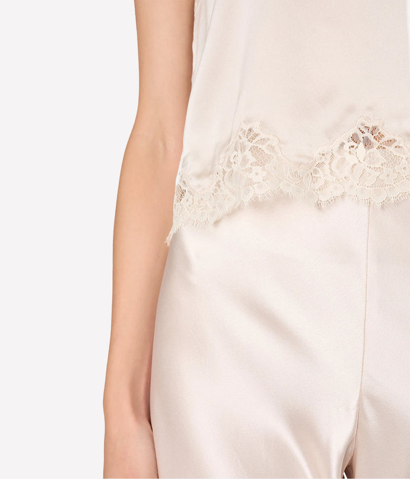 Close-up of a person wearing a light cream satin garment with a decorative lace trim at the waist