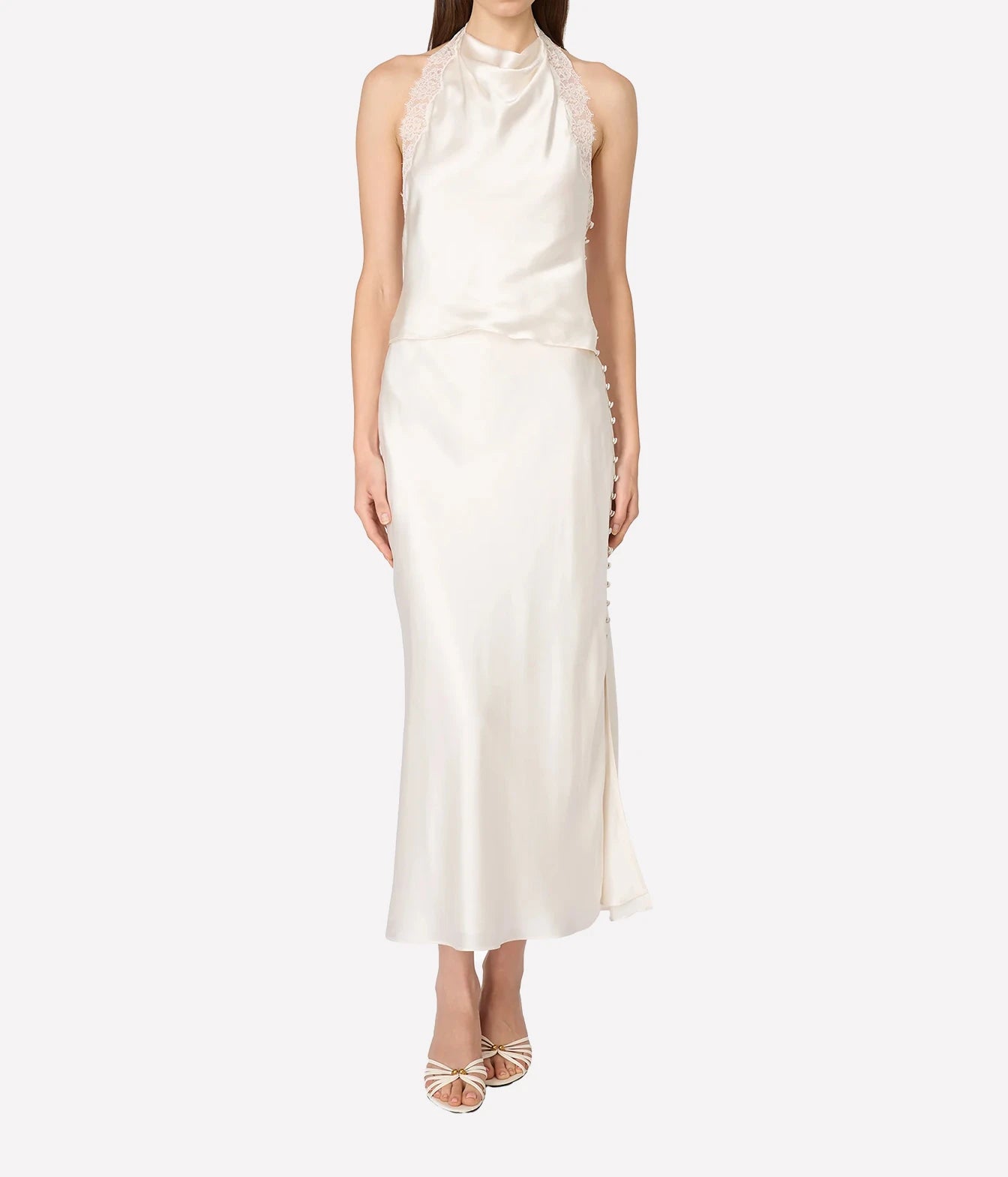A model wearing a sleeveless high-neck satin dress in off-white