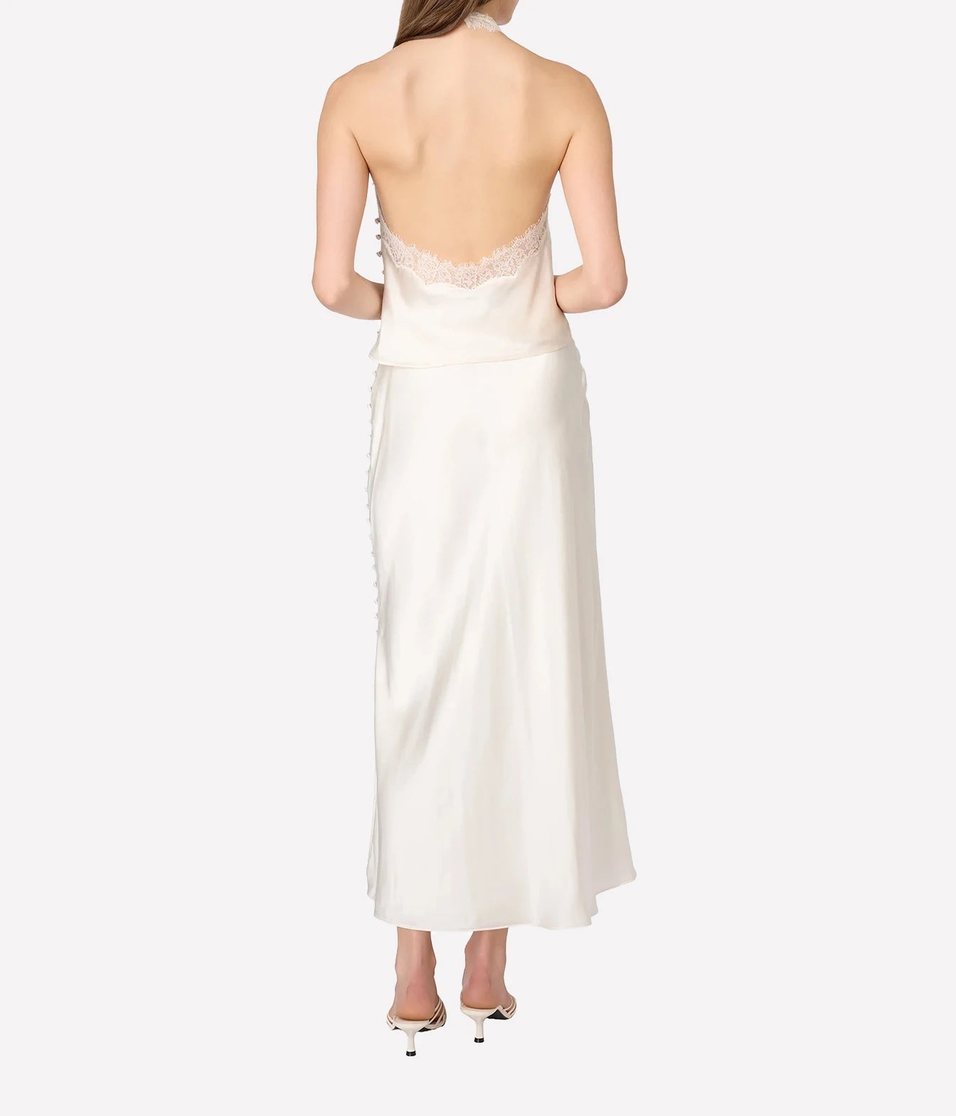 A woman shown from the back wearing a strapless ivory satin top with a lace-trimmed open back and side buttons
