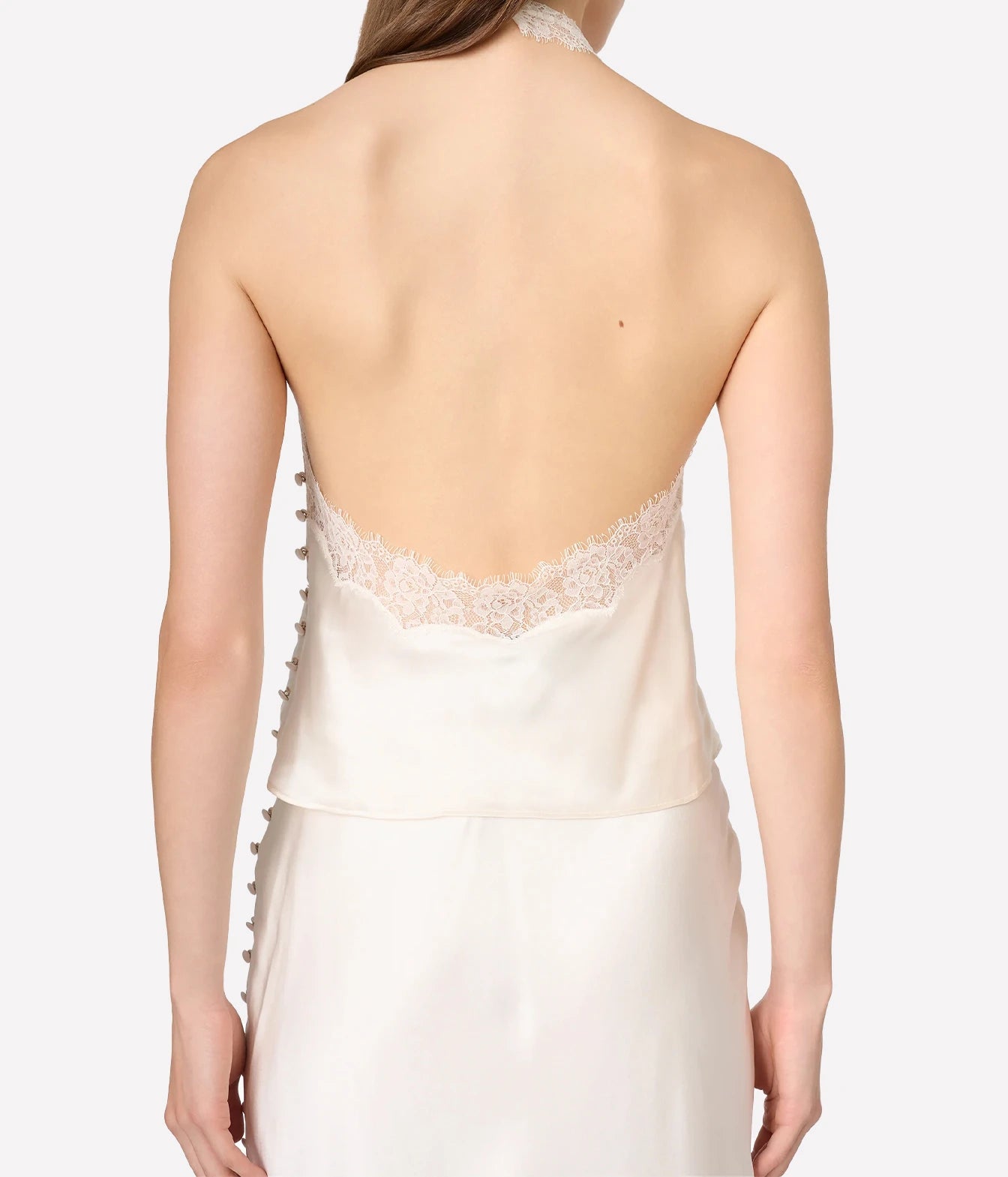 Back view of a model wearing a satin slip dress with a lace-trimmed open back and side buttons