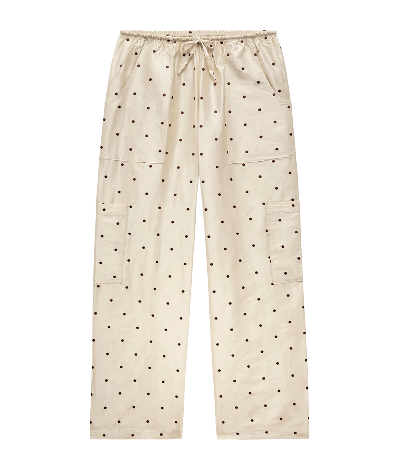 Cream-colored pants with a black polka dot pattern, featuring an elastic drawstring waist, side cargo pockets, and a relaxed straight-leg fit, shown against a plain white background.