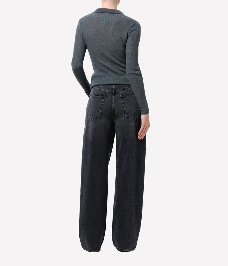 A model shown from the back wearing a dark gray long-sleeve knit top and dark wide-leg denim jeans against a light gray studio background.