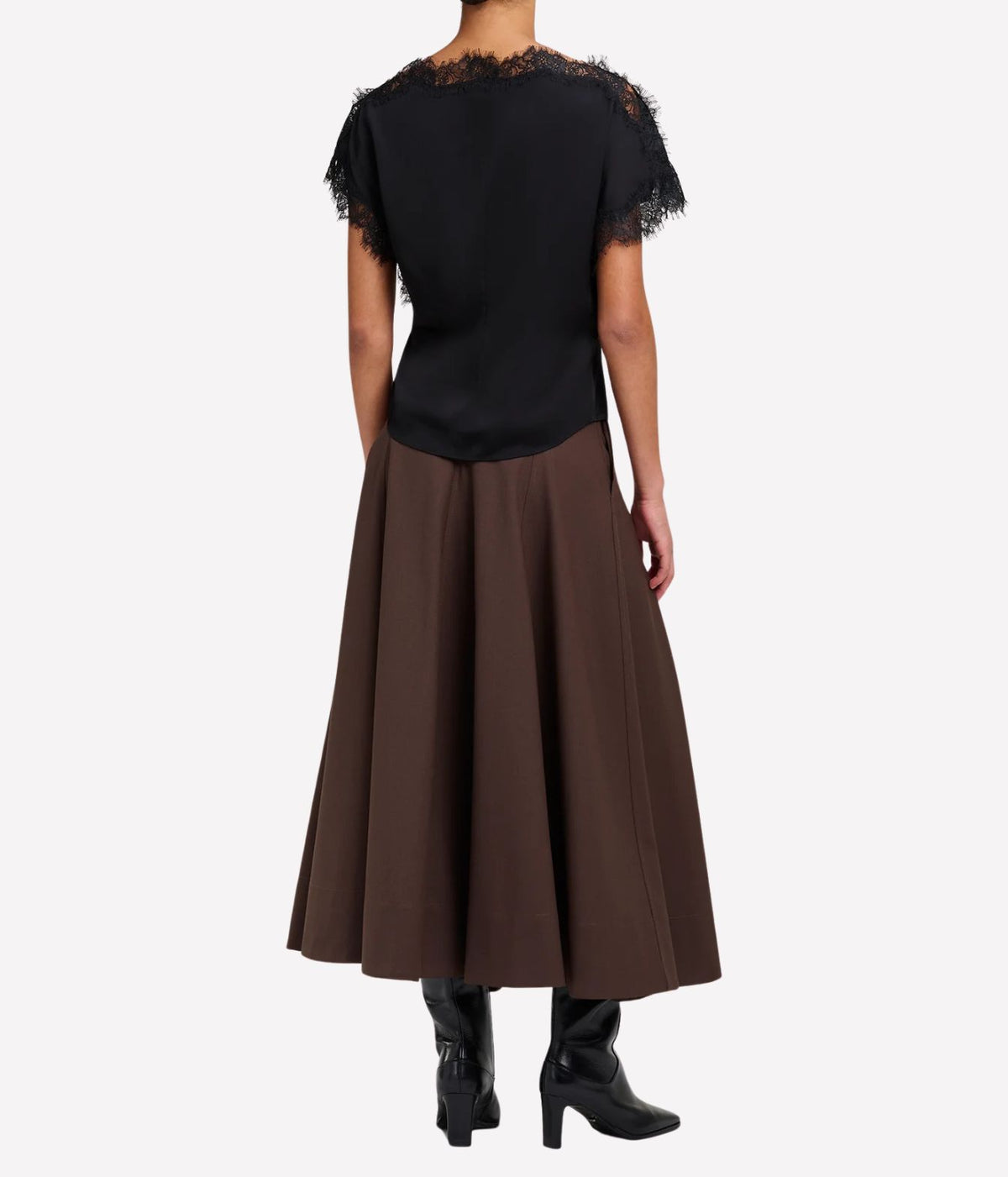 Back view of a model wearing the A.L.C. Luna Top in Black with a full chocolate brown midi skirt and black heeled ankle boots, showing the lace-trimmed cap sleeves