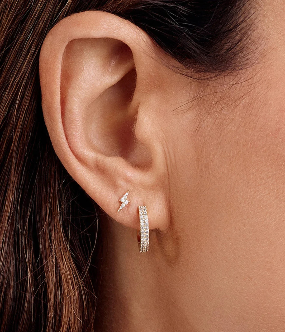 Close-up of a model with dark hair wearing the Gorjana Wilder Shimmer Bar Huggies in Yellow Gold in the lobe, showing the sparkle of the stone bar