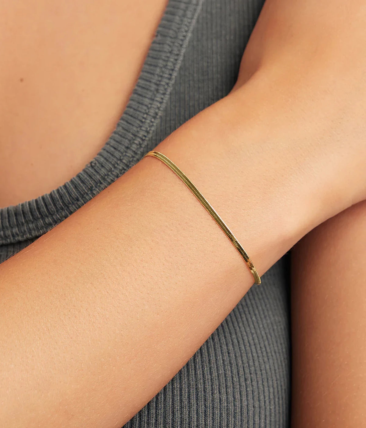 Close-up of a model's wrist wearing the Gorjana Venice Mini Bracelet in Yellow Gold with a charcoal ribbed knit top