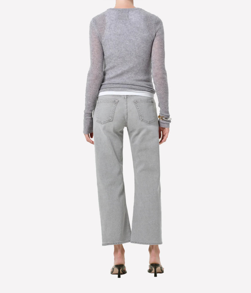 Rear view of a model wearing light gray wide-leg jeans, a heather gray long-sleeve knit top, and black heeled sandals against a plain light gray background.