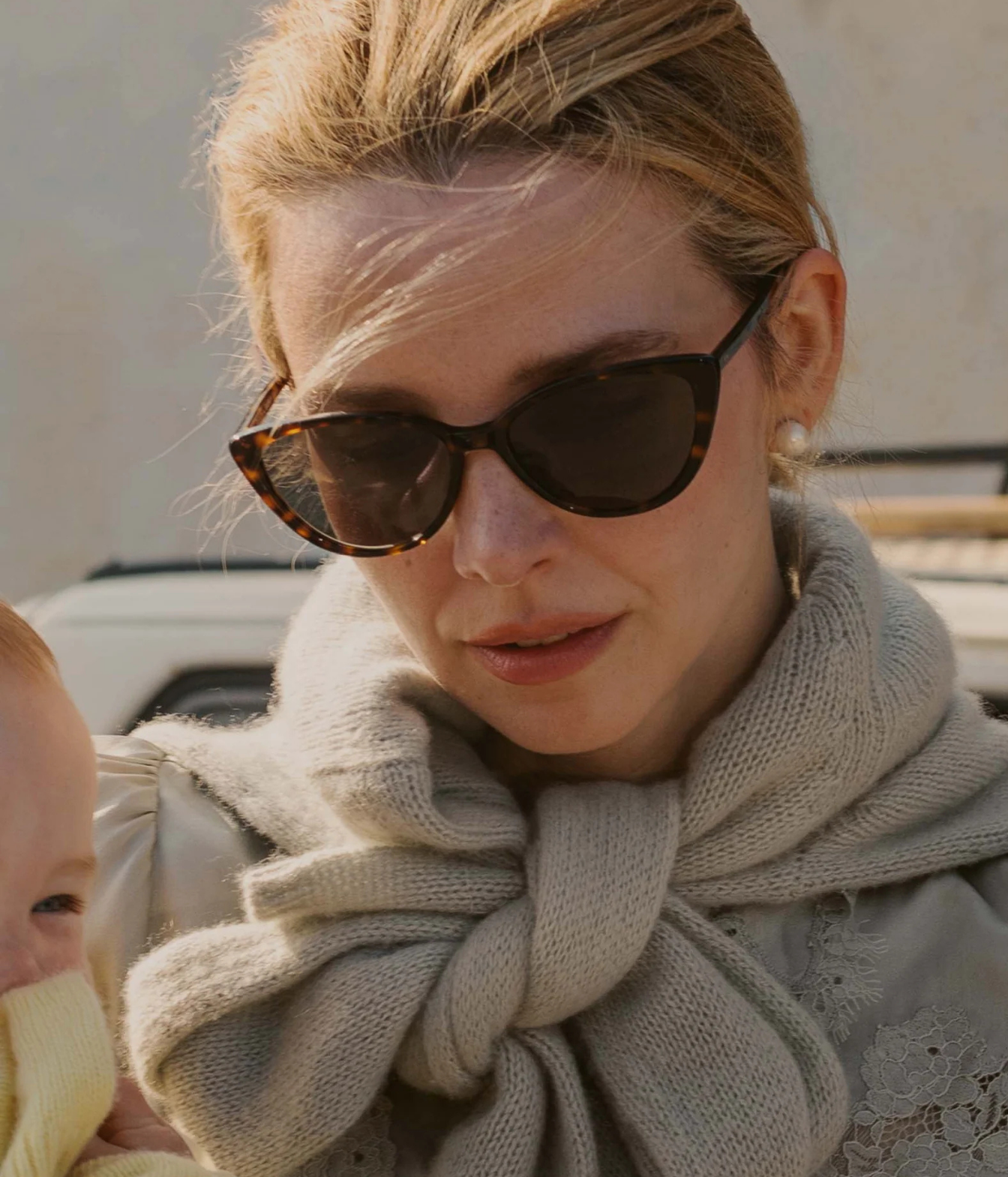 A close-up lifestyle shot of a woman wearing tortoiseshell cat-eye sunglasses 