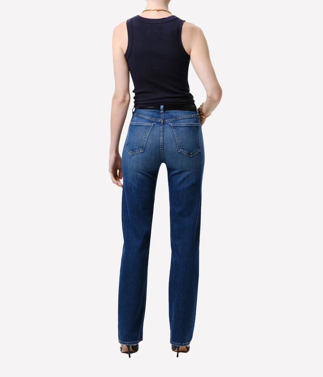 Rear view of a model wearing dark blue straight-leg jeans and a black sleeveless top against a light gray background.