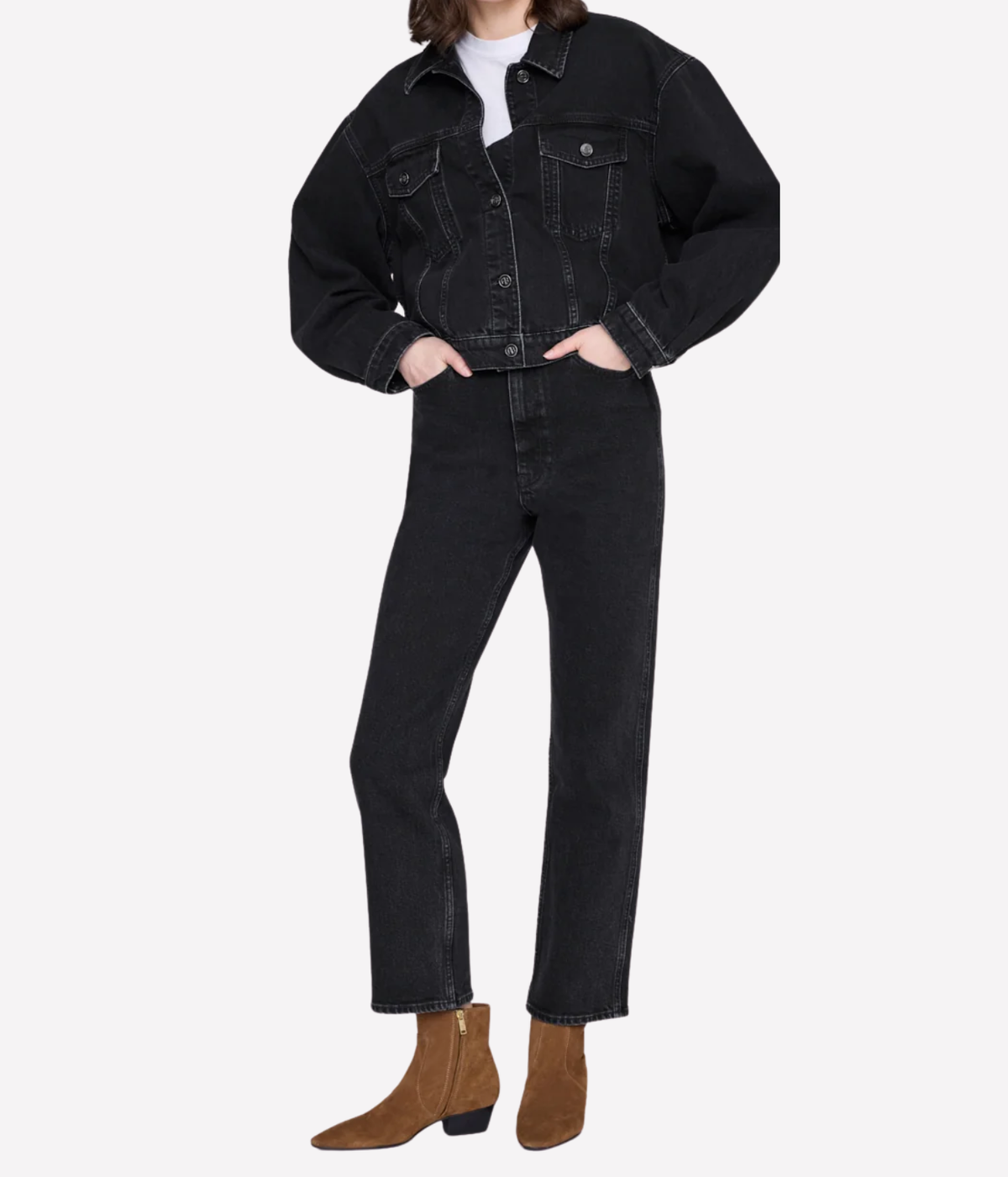 A model wearing a black cropped denim jacket, black straight-leg jeans, and brown suede ankle boots, shown against a plain light gray studio background.