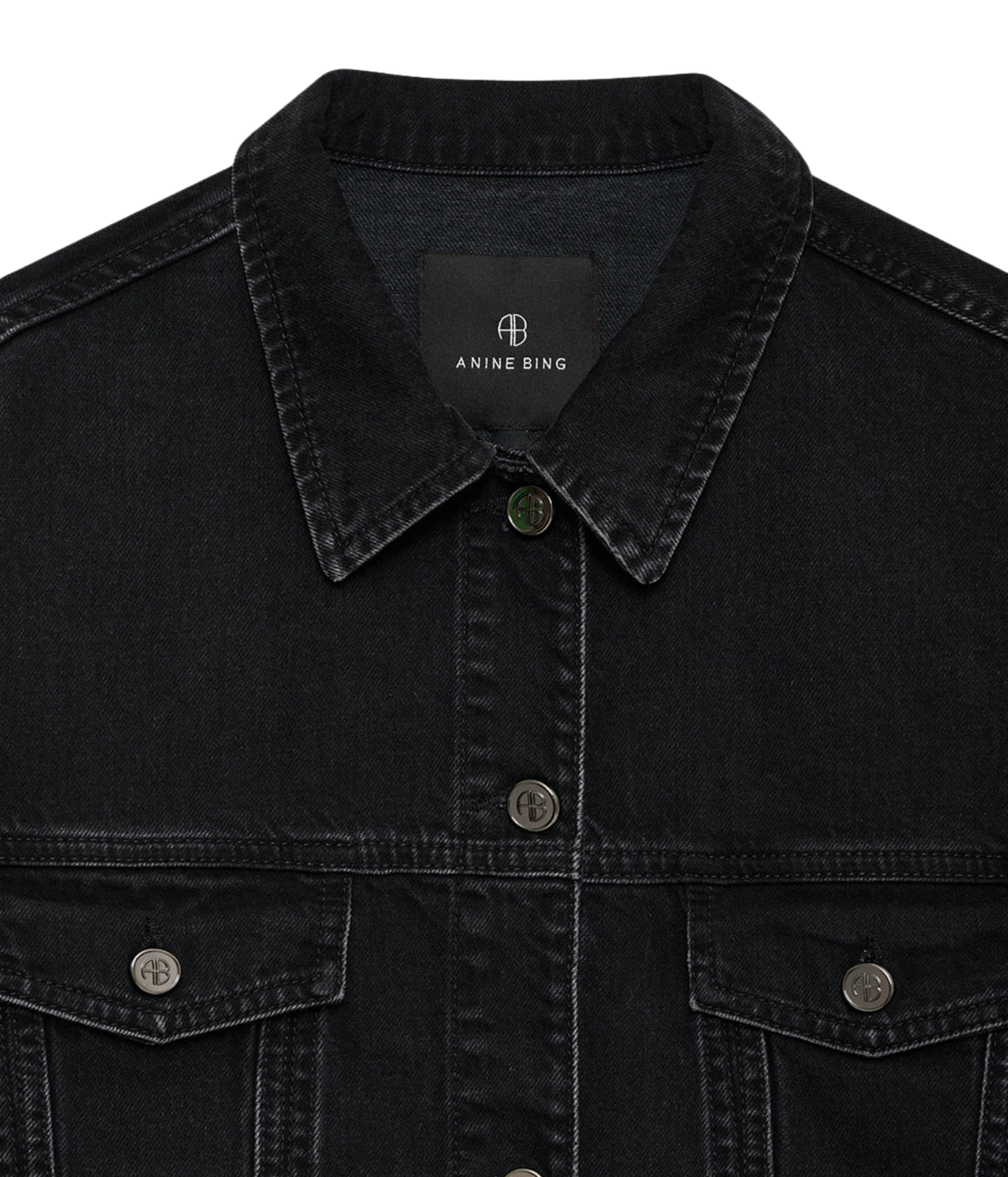Close-up of a black denim jacket with a pointed collar, button front, and two chest pockets, shown on a white background. The inner neck label reads Anine Bing.