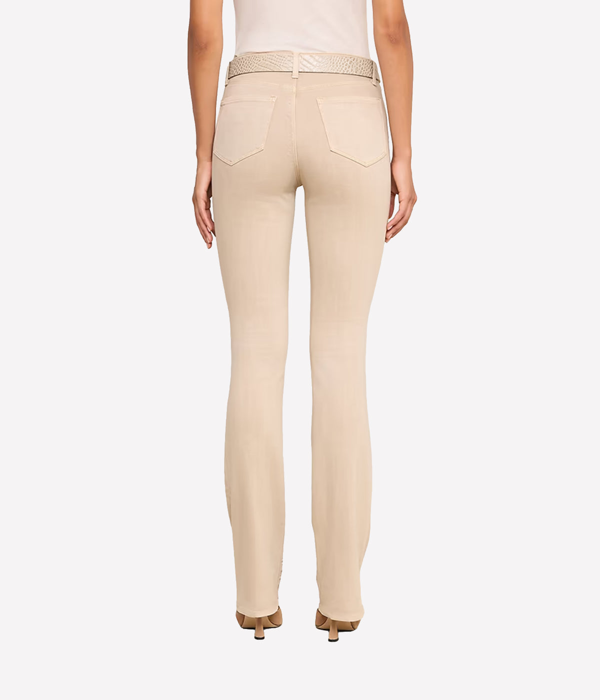 Rear view of a model wearing the L'AGENCE Selma Bootcut Jean in Biscuit with a matching woven belt, paired with a white top and brown heels.