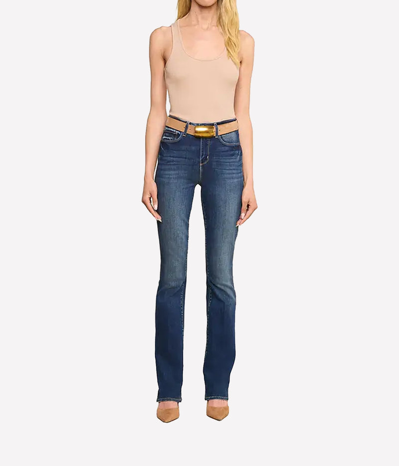 A model wearing blue high-rise jeans with a gold-tone belt, paired with a beige tank top and beige heels.