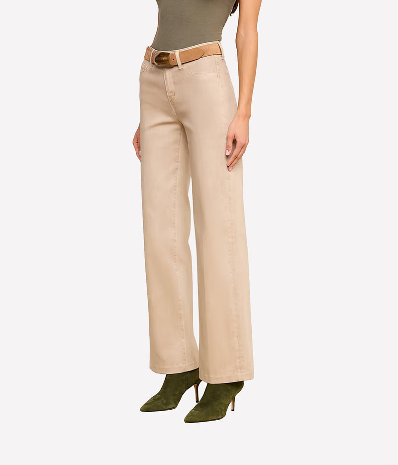 Three-quarter view of a model wearing the L’AGENCE Scottie Coated Wide-Leg Jeans in Antique Birch with a tan belt and olive suede boots.