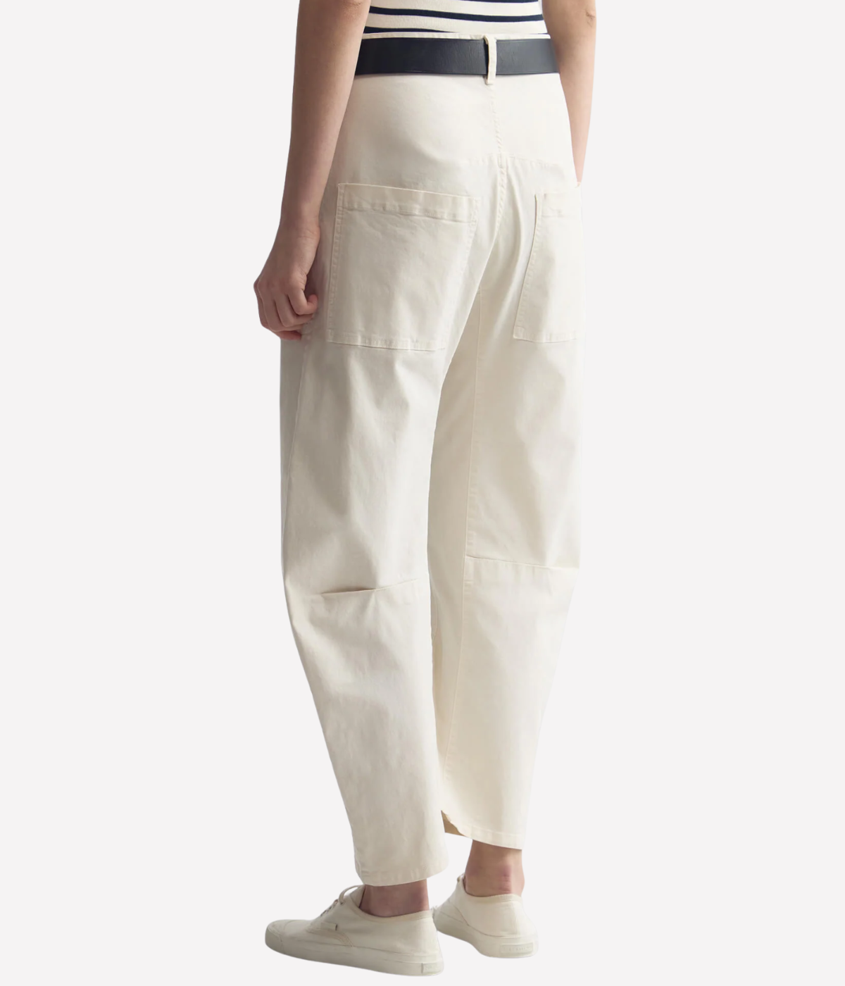 Nili Lotan Shon Pant in Stone, lower half angled back view on model, highlighting curved barrel-leg shape, back patch pocket detail, and seam construction.
