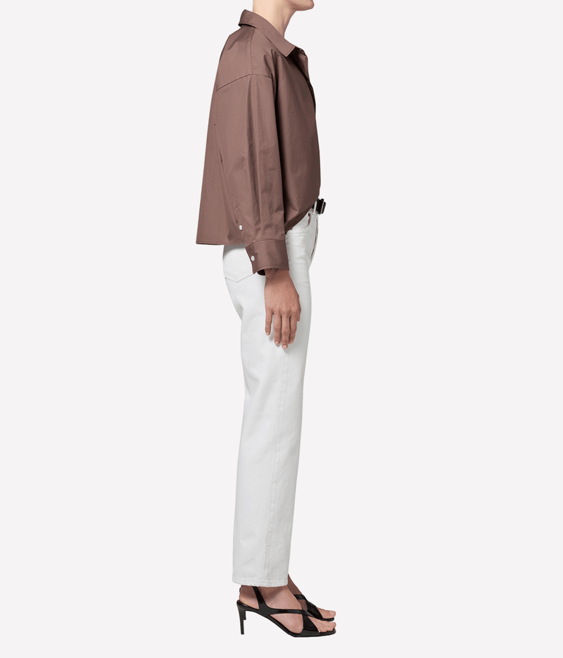 Side profile of a model wearing the Citizens Of Humanity 90s French High Rise Straight in vintage white with an oversized brown shirt and black strappy heels, showing the straight silhouette from hip to hem