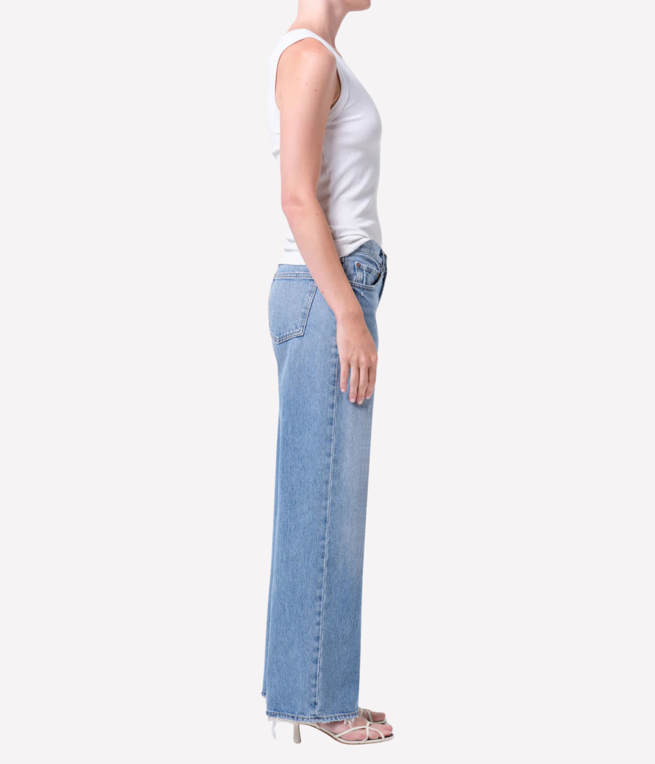 A model wearing light-wash blue straight-leg jeans standing against a plain light gray studio background.