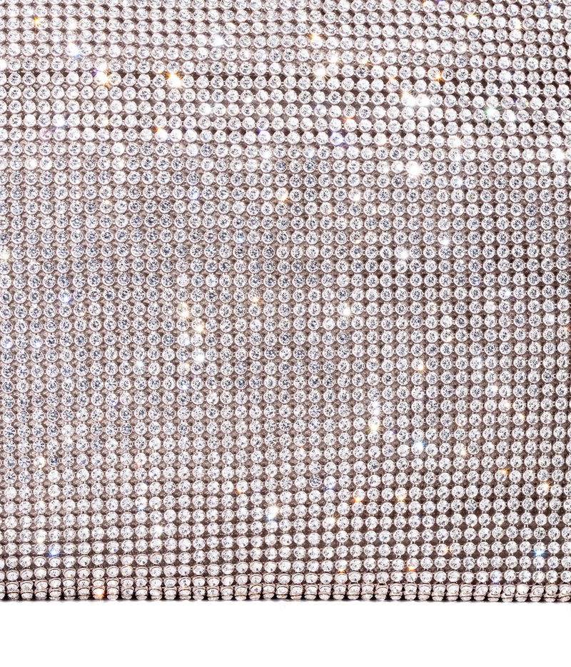 A close-up of a rhinestone-covered surface with dense rows of clear faceted stones in a silver-toned setting, creating a sparkling light-reflective texture against a white background.