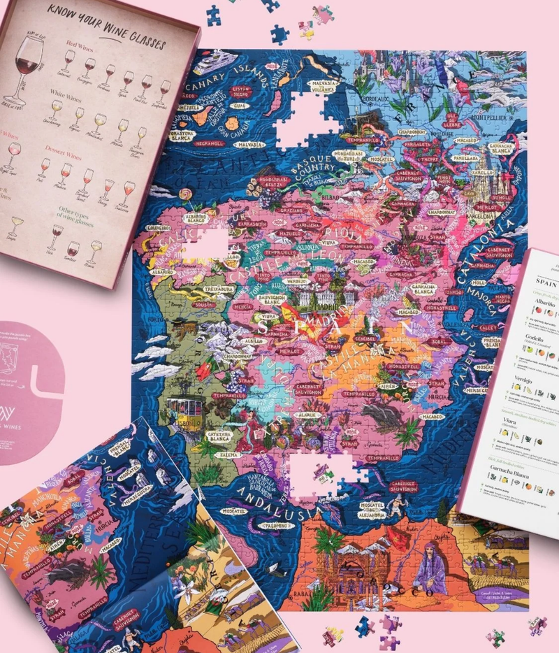 Water and Wines 1000 Piece Puzzle of Spain nearly complete and laid flat beside the open box lid with its wine glass guide, the grape profile card, the box stand and the fold-out poster