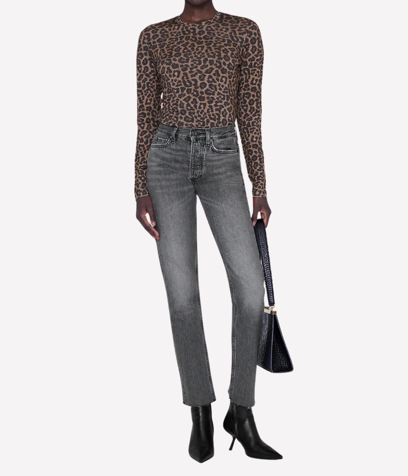 A model wearing a brown and black leopard print long-sleeve top, gray high-waisted straight-leg jeans, black pointed-toe ankle boots, and holding a black handbag against a light gray background.