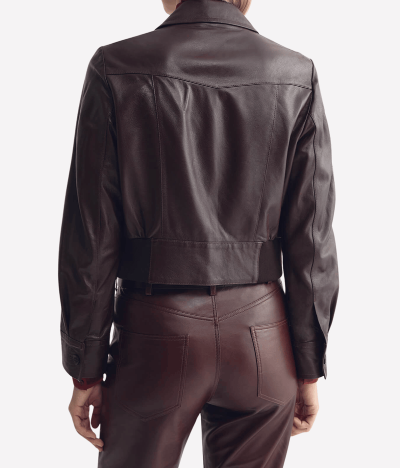 Back view of a model wearing the Nili Lotan Charly Leather Jacket in Bordeaux with matching leather trousers, showing the Western back yoke, two-panel back and banded hem