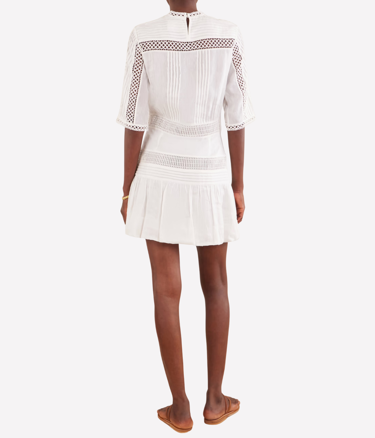 A woman modeling the Isabel Marant Paige Dress In White, a elbow-length sleeve mini dress with lace and crochet detailing, shown from the back