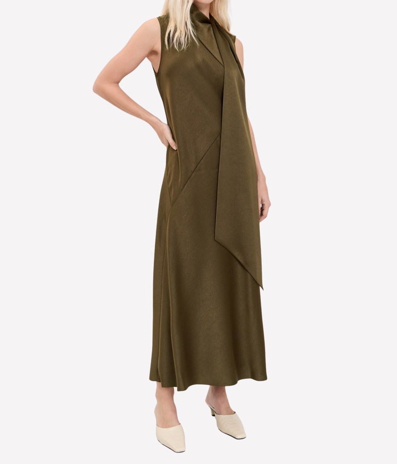 Front view of a model wearing the Vince Draped Scarf Tie Dress In Cypress with one hand on her hip and the scarf tie falling over one shoulder, with cream flats