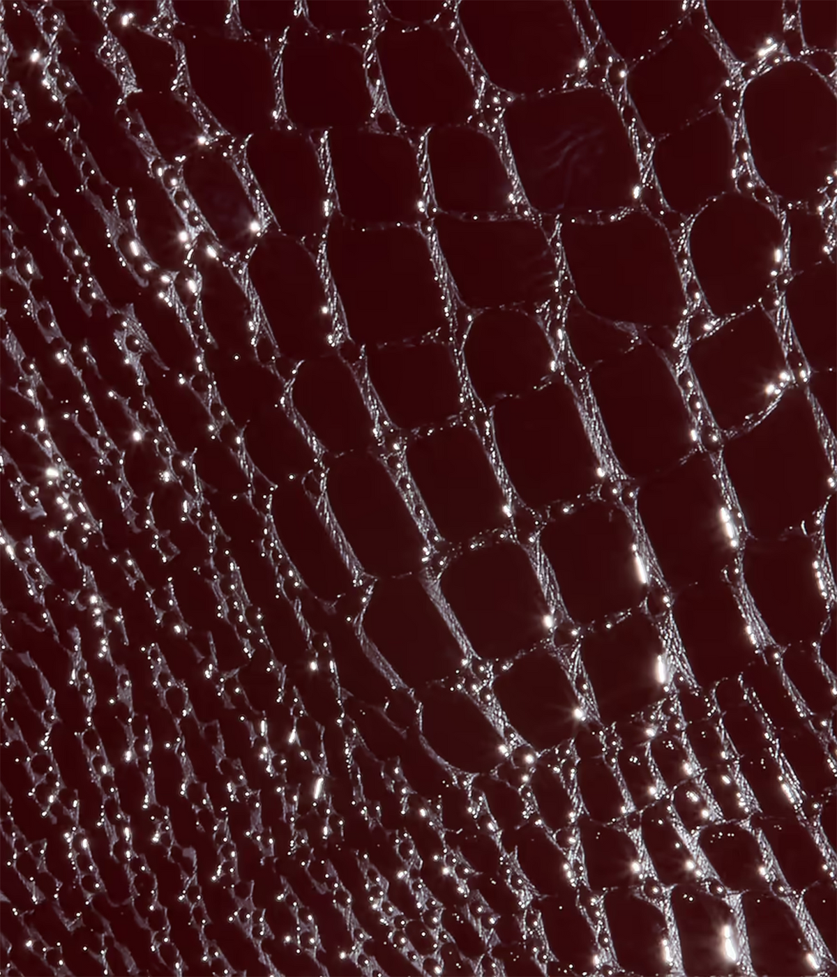 A close-up of a dark burgundy and deep red croc-embossed vegan leather
