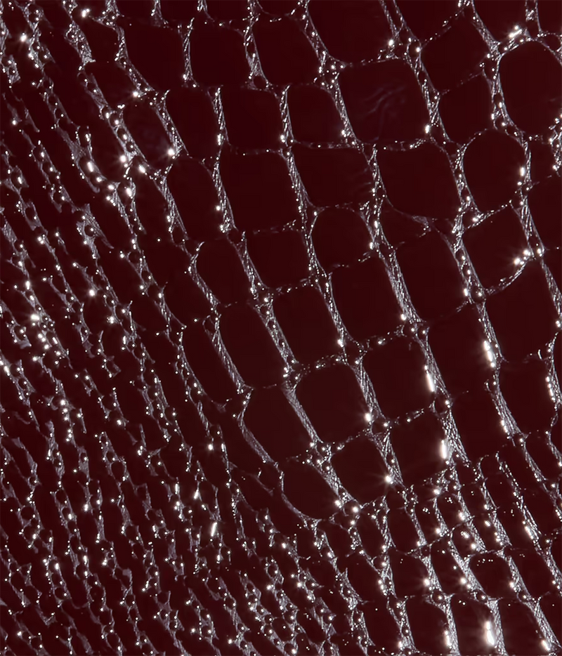 A close-up of a dark burgundy and deep red croc-embossed vegan leather