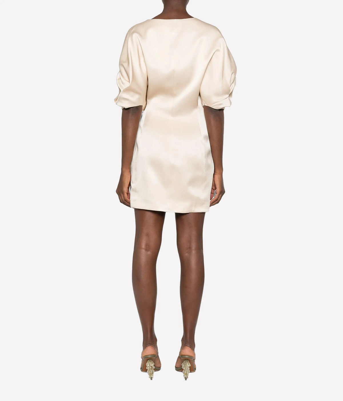 Back view of a model wearing the Raquel Diniz Anastasia Short Dress in Vanilla with strappy heeled sandals, showing the puffed sleeves and fitted mini silhouette