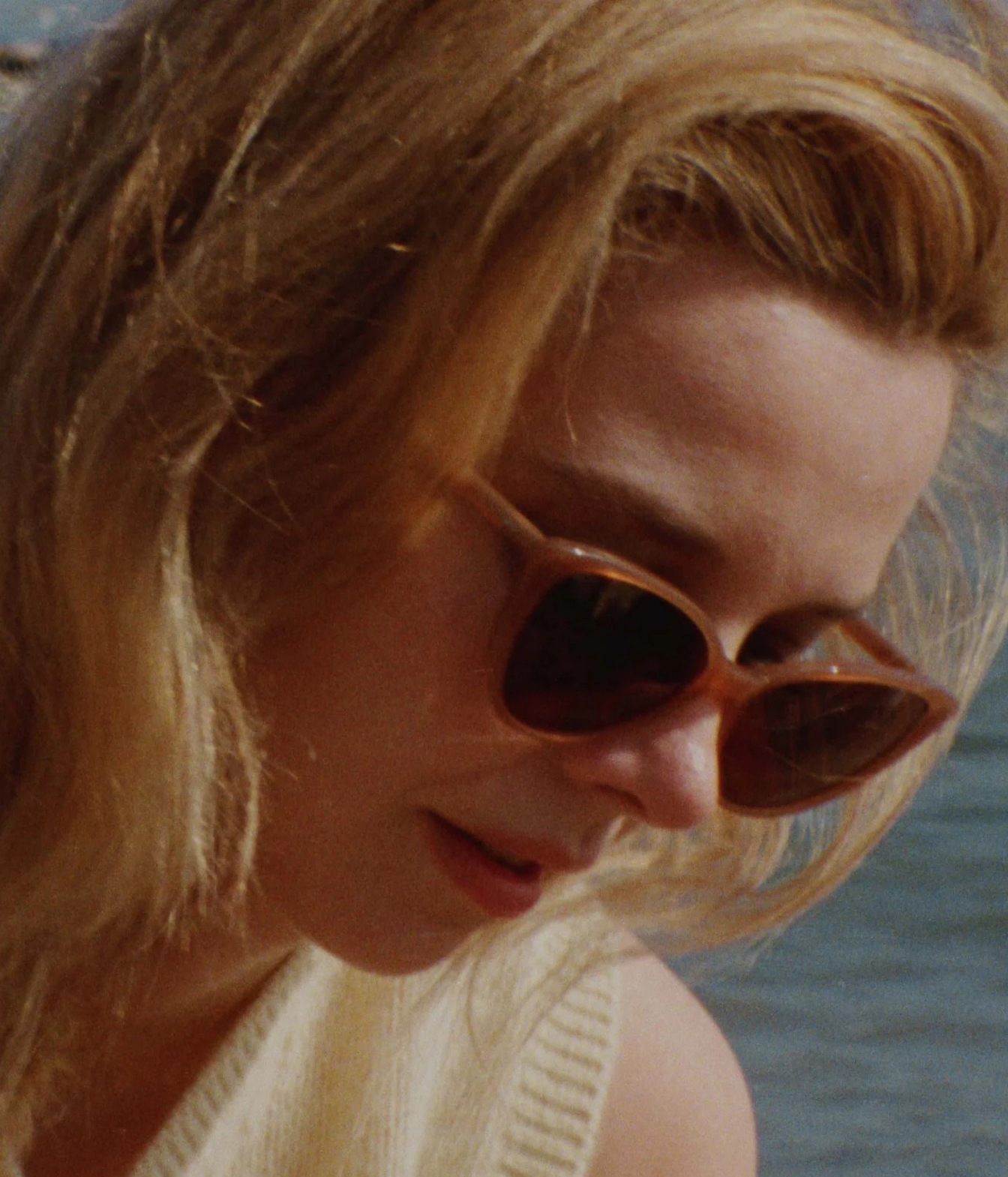 A close-up shot of a woman with blonde hair wearing GLCO x Doen Doyenne Sun 53 Mink Sunglasses