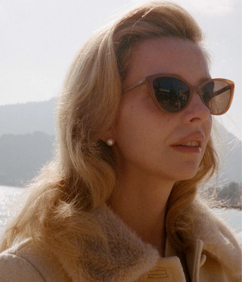 A close-up portrait of a woman wearing brown cat-eye sunglasses