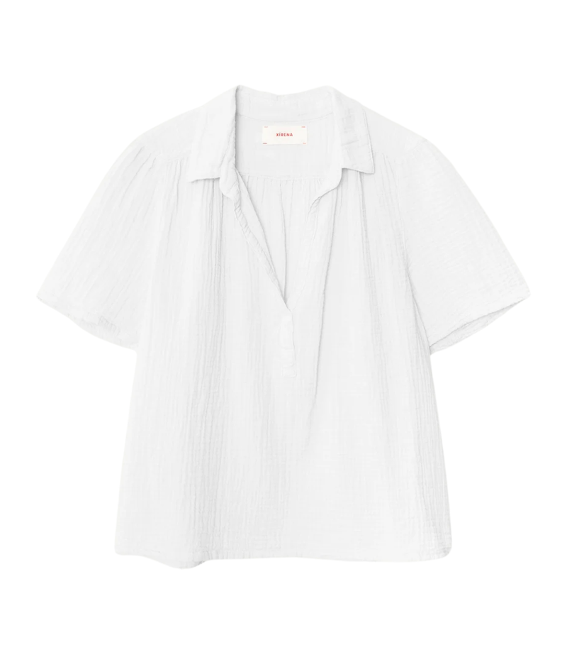 Xirena Rylee Top in Pale Sky laid flat, showing the spread collar, open placket and short sleeves with subtle shirring at the yoke