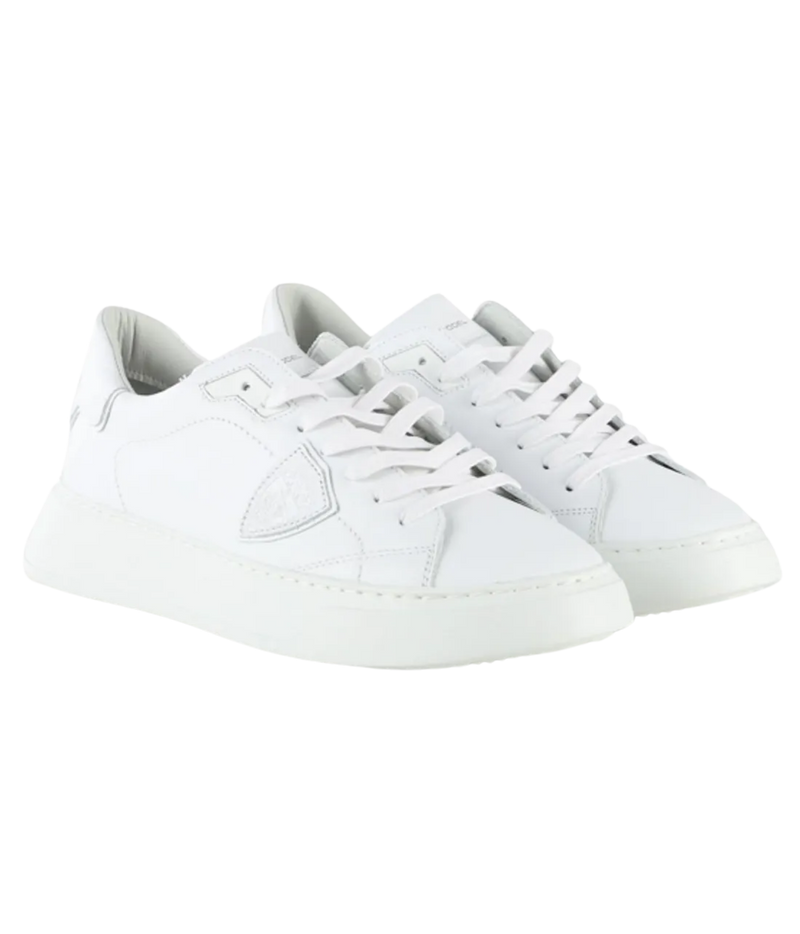 A pair of white leather low-top sneakers with matching white laces and thick white soles