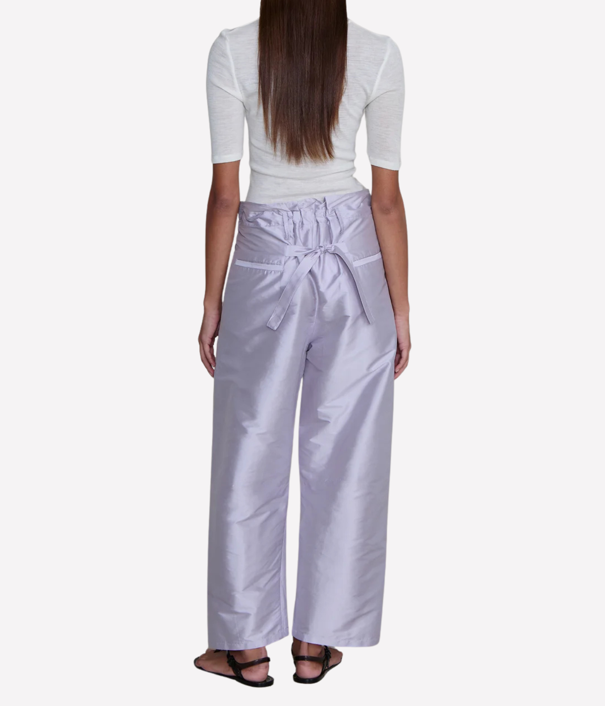 Back view of a model wearing the Chan Luu Techno Taffeta Barrel Pant in Lilac with a fitted white short-sleeve top, showing the back waist tie, gathered waistband and back pockets