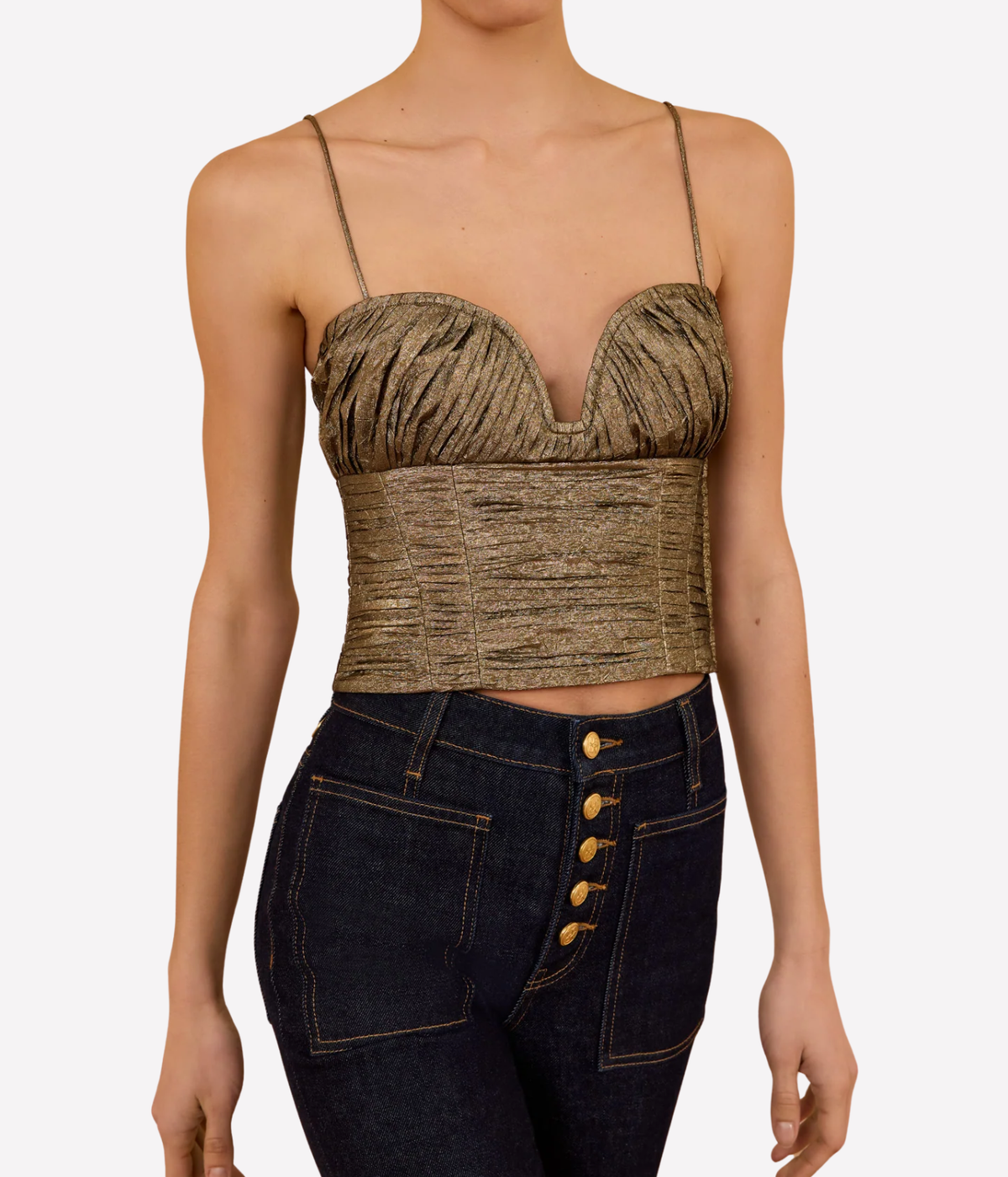 Front view of a model wearing the Ulla Johnson Vina Taffeta Cropped Bustier Top in Light Gold with dark indigo high-waisted jeans featuring a gold button fly