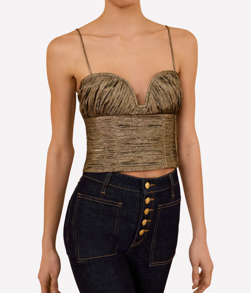 Front view of a model wearing the Ulla Johnson Vina Taffeta Cropped Bustier Top in Light Gold with dark indigo high-waisted jeans featuring a gold button fly