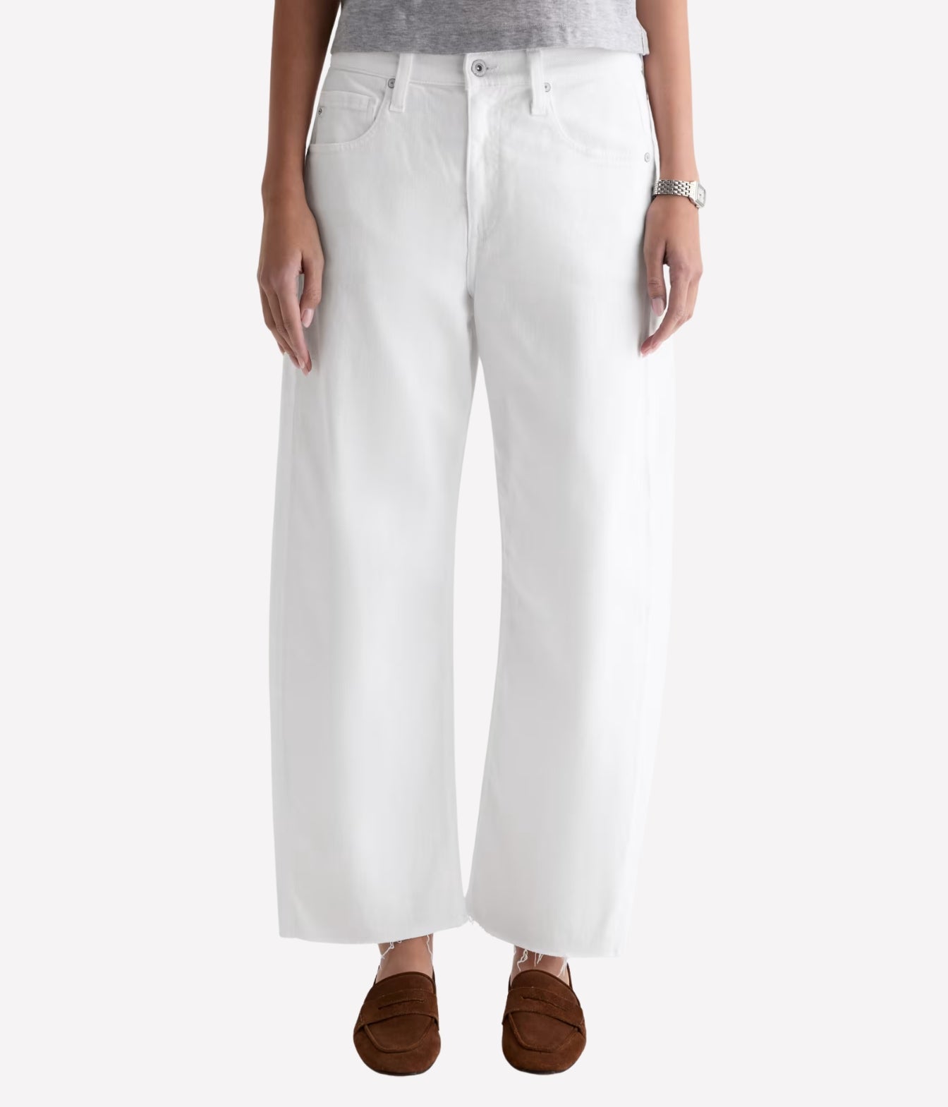 White wide-leg cropped jeans shown on a model from the waist down, paired with a gray top and brown slip-on shoes against a light gray background.