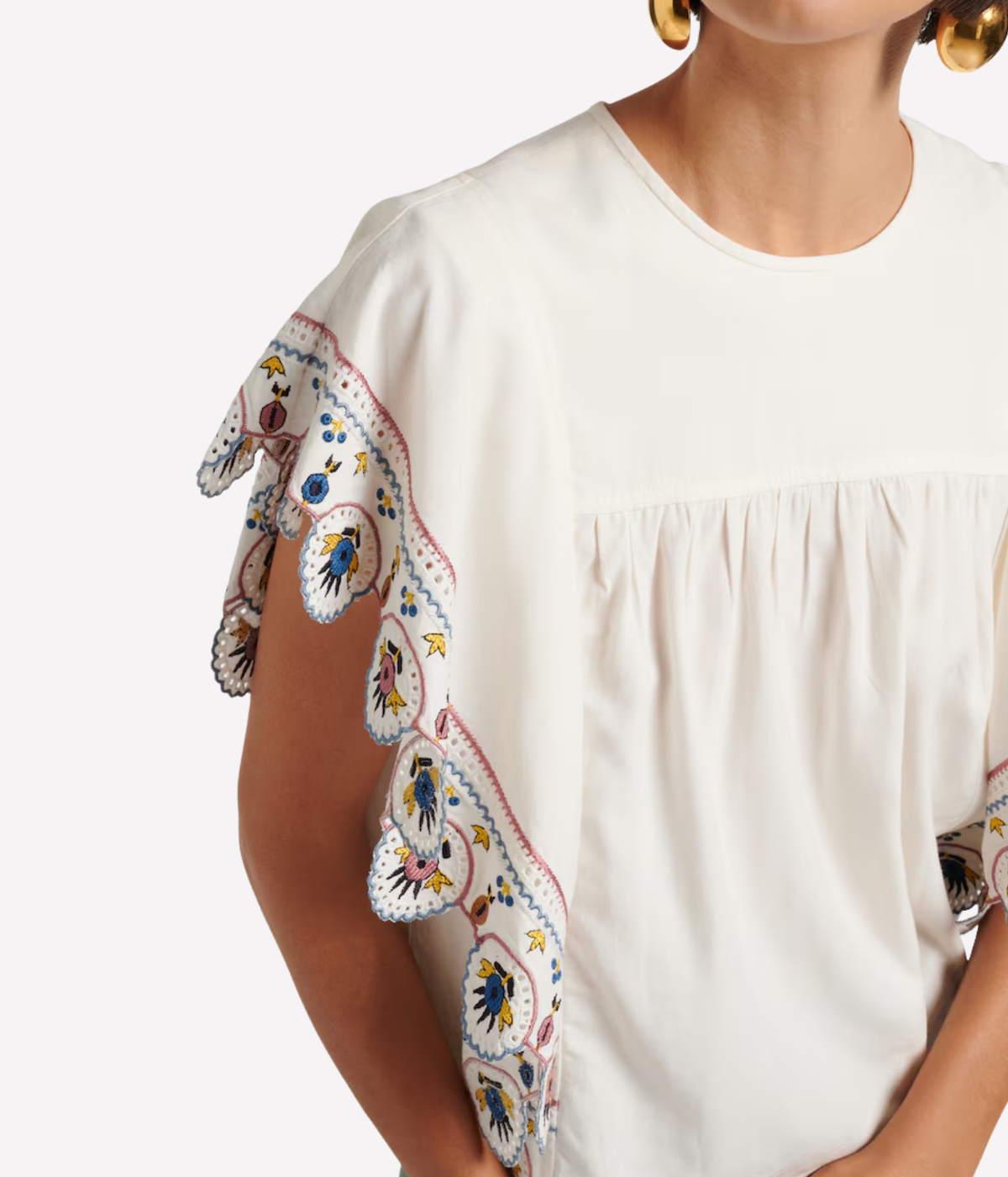 A close-up of a model wearing a cream-coloured blouse with distinctive ruffled sleeves - Marlie Top In Ecru