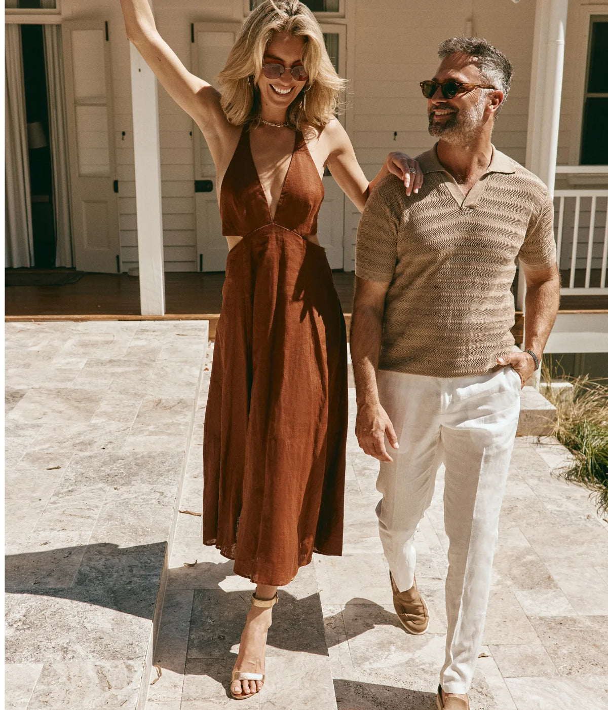 Mr Leight Cora S Sun 55 In Abalone-White Gold, worn on model with a rust halter midi dress, walking arm in arm with a man in a striped knit polo