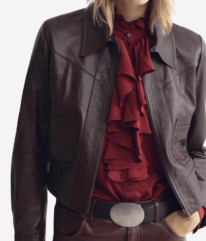 Model wearing the Nili Lotan Charly Leather Jacket in Bordeaux open over a red ruffle-front blouse, showing the yoke detail and patch pockets with a silver oval belt buckle
