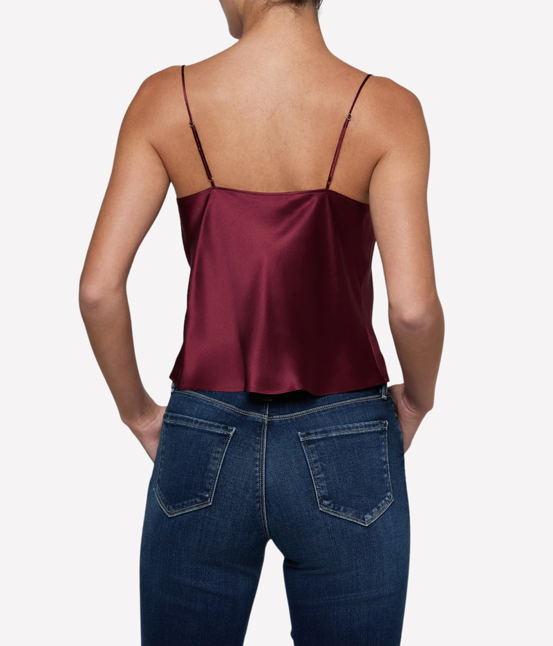 A woman shown from the back wearing a burgundy silk spaghetti-strap top and dark blue jeans.