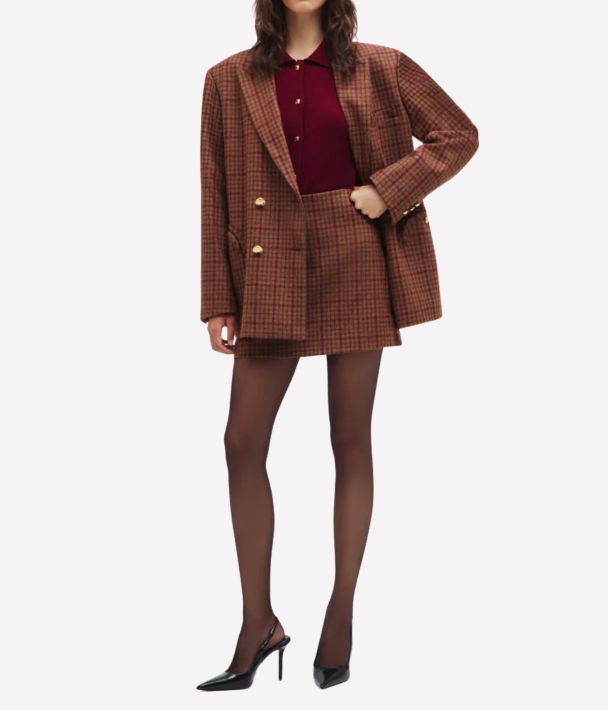 A model wearing the Blazé Milano Sweet Sea Nightbreak Blazer in Cinnamon Mix and matching mini skirt set, styled with a burgundy polo shirt, sheer black tights, and black high heels