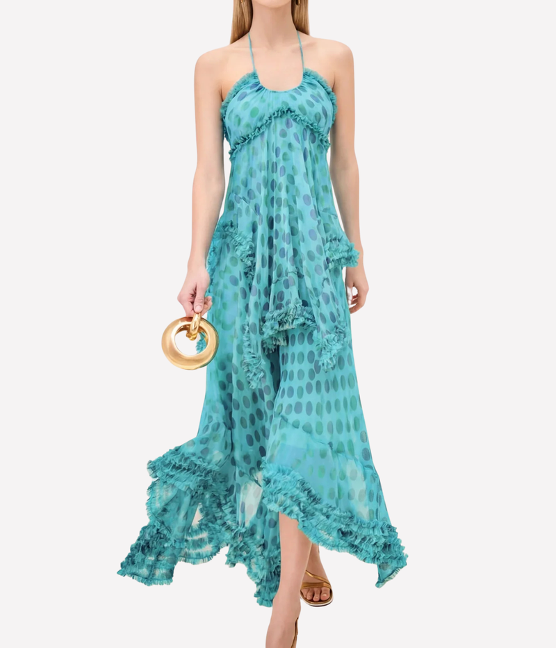Woman wearing a turquoise dress with ruffled details on a white background