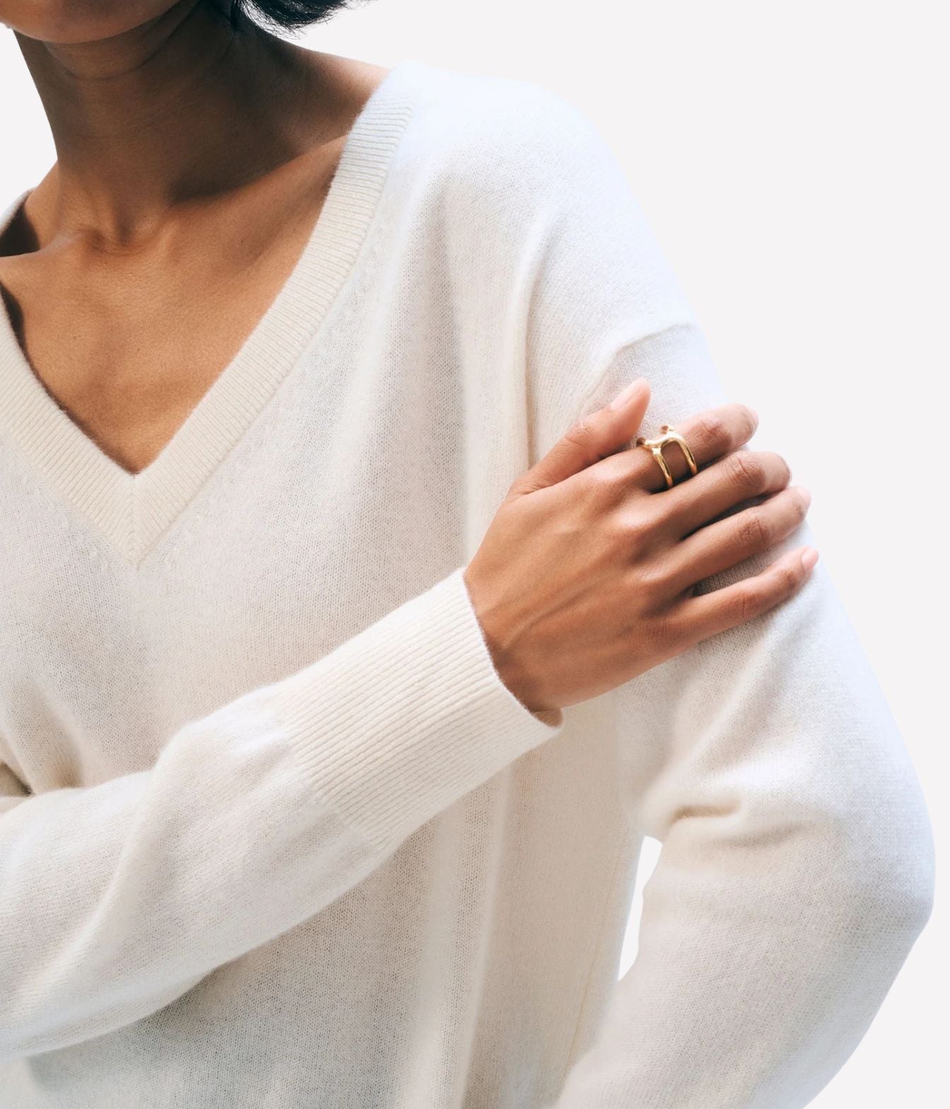 A close-up of a person wearing a soft cream V-neck knit sweater