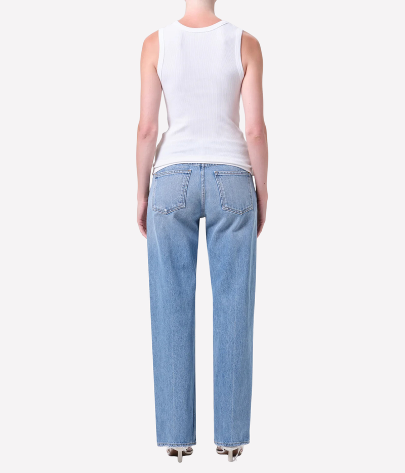 A model wearing light-wash blue straight-leg jeans standing against a plain light gray studio background.